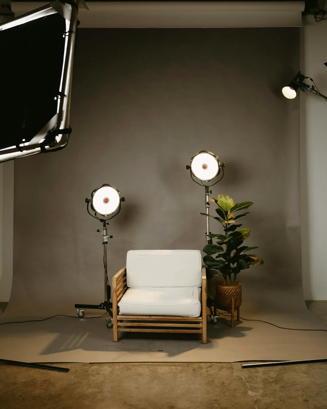 Estúdio de fotografia com duas luzes de apoio e uma poltrona branca