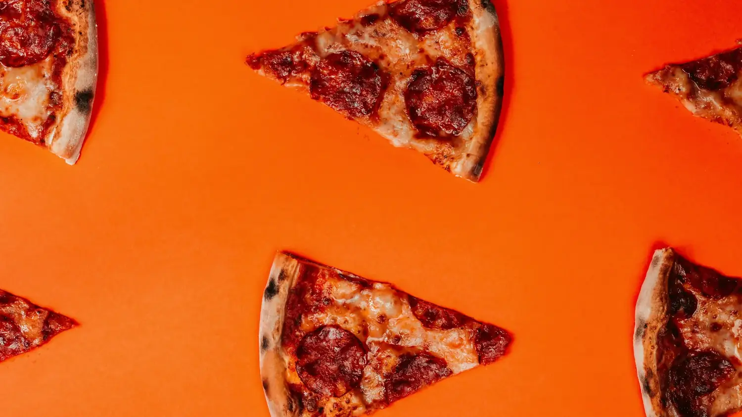Fatias de pizza espalhadas sobre fundo laranja